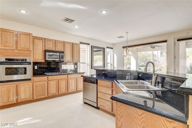 kitchen featuring sink, tasteful backsplash, decorative light fixtures, appliances with stainless steel finishes, and dark stone counters