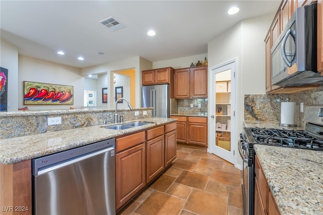 kitchen featuring light stone counters, appliances with stainless steel finishes, backsplash, and sink