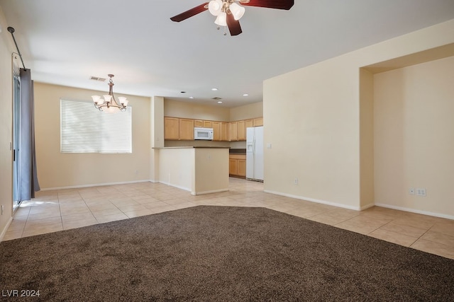 unfurnished living room featuring a barn door, ceiling fan with notable chandelier, and light carpet