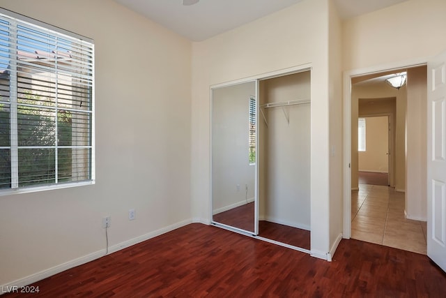 unfurnished bedroom with a closet and dark hardwood / wood-style floors