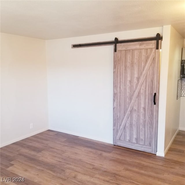 spare room with a barn door and hardwood / wood-style floors