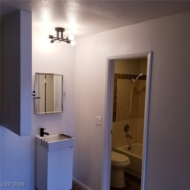 full bathroom with vanity, tiled shower / bath, a textured ceiling, and toilet