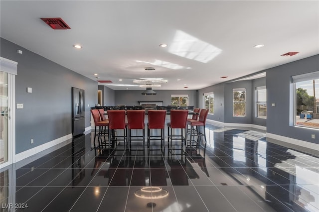 kitchen featuring dark tile patterned floors, a kitchen island, stainless steel fridge with ice dispenser, and a breakfast bar area