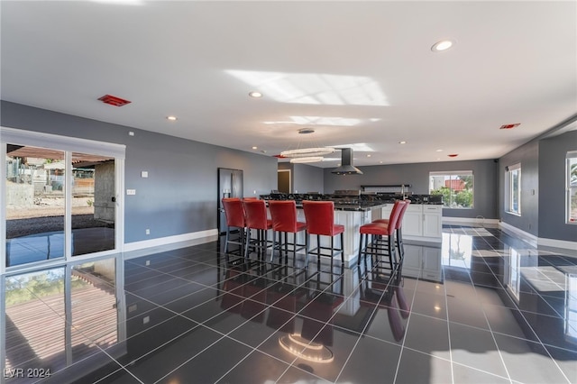 bar with wall chimney exhaust hood, dark tile patterned floors, and white cabinetry