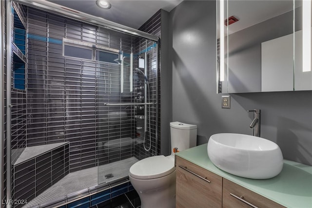 bathroom featuring vanity, a shower with door, and toilet