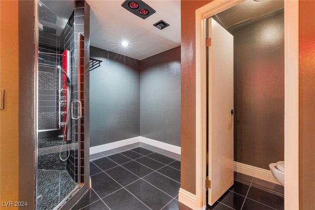 bathroom featuring a tile shower, toilet, and tile patterned floors