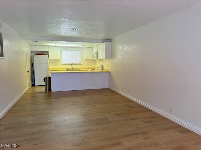 kitchen featuring light wood-type flooring, sink, white appliances, and white cabinetry