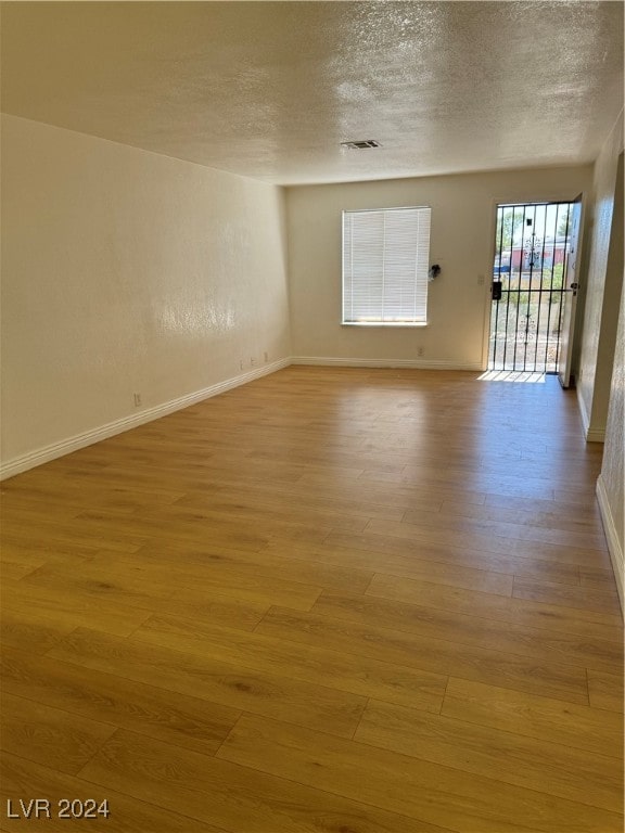 spare room featuring a textured ceiling and light wood-type flooring