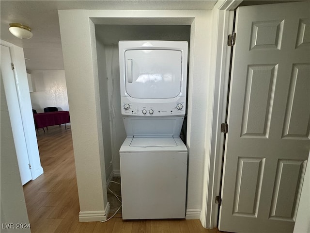 laundry room with stacked washer and dryer and light hardwood / wood-style flooring