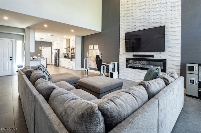 tiled living room featuring a high ceiling and a stone fireplace