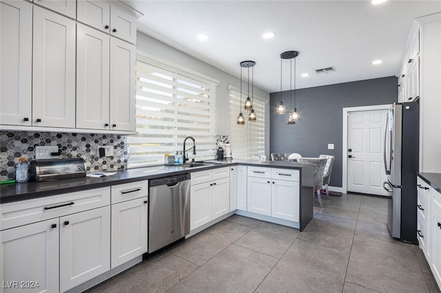 kitchen with decorative backsplash, white cabinets, stainless steel appliances, decorative light fixtures, and sink