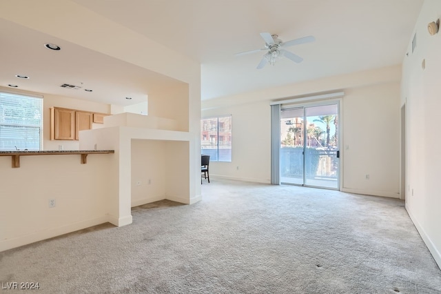 unfurnished living room featuring light carpet and ceiling fan