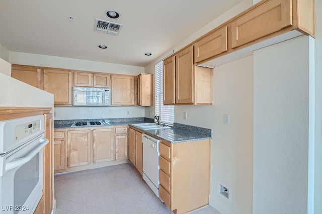 kitchen featuring white appliances, dark stone countertops, sink, and light brown cabinets