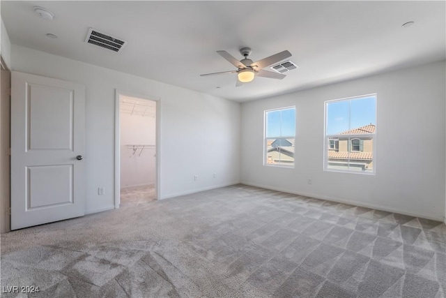 unfurnished bedroom with ceiling fan, carpet floors, a walk in closet, and visible vents