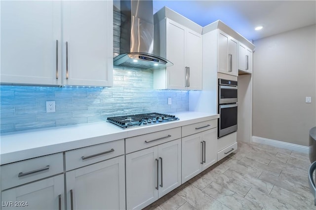 kitchen with tasteful backsplash, wall chimney exhaust hood, stainless steel appliances, light countertops, and white cabinetry