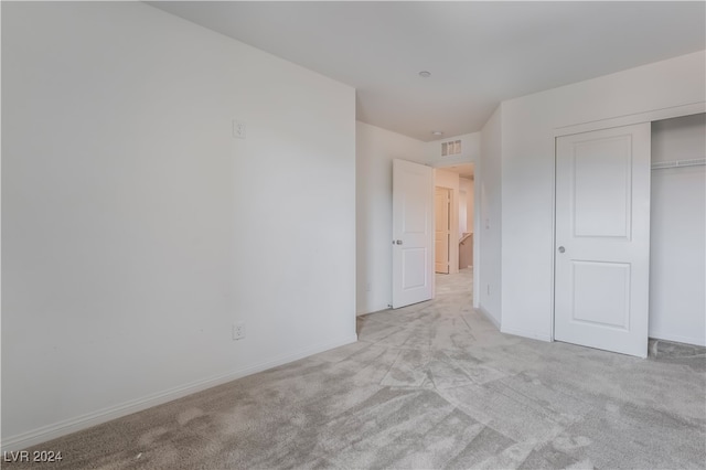 unfurnished bedroom with a closet and light colored carpet