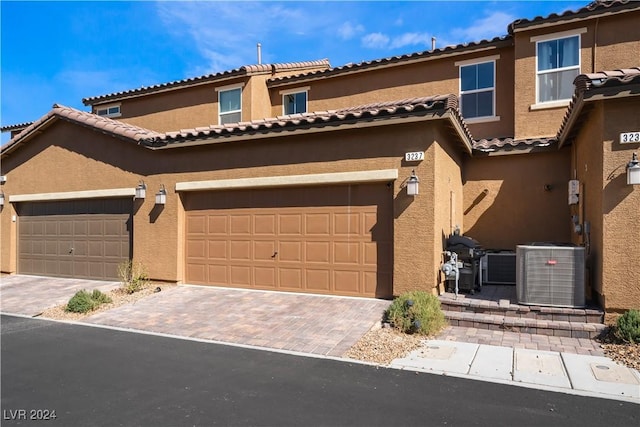 view of front facade featuring central AC unit, decorative driveway, and stucco siding