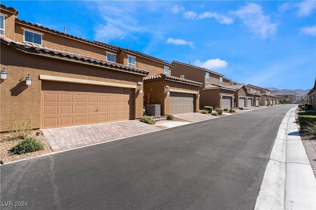 view of front of house with a garage and central air condition unit