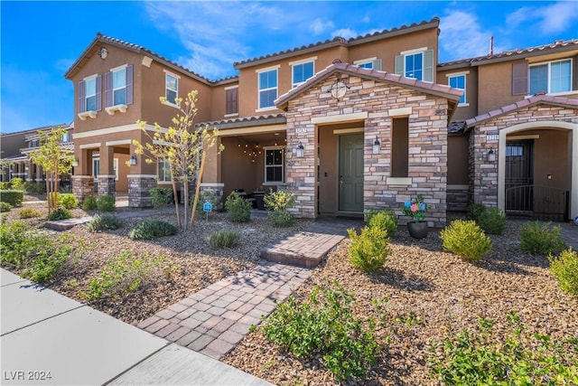 view of front of property featuring stone siding, a tile roof, and stucco siding