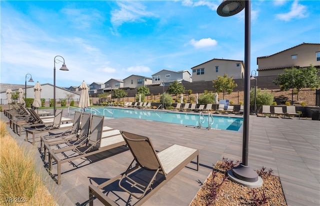 community pool featuring a patio, fence, and a residential view