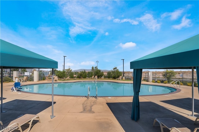 community pool with a patio, fence, and a mountain view