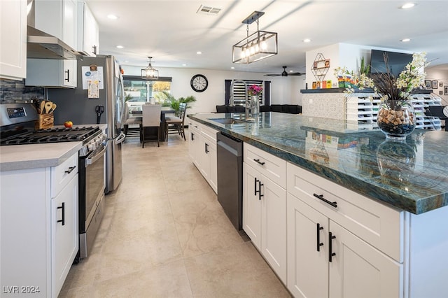 kitchen featuring white cabinetry, ceiling fan, stainless steel appliances, and a large island