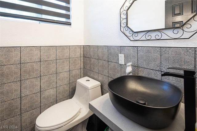 bathroom featuring sink, tile walls, and toilet