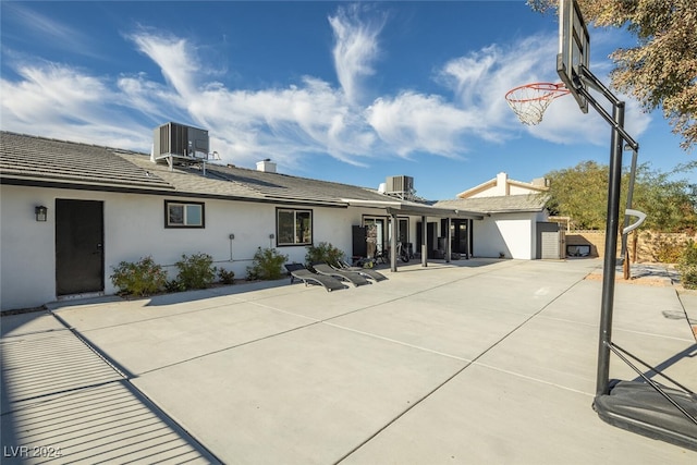 exterior space with basketball hoop, central AC unit, and a patio area