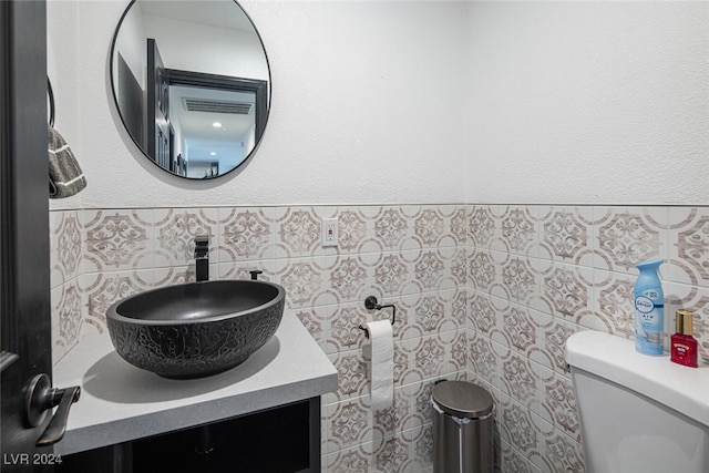 bathroom featuring vanity, toilet, and tile walls