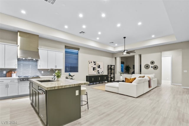 kitchen with a breakfast bar, white cabinetry, sink, and a kitchen island with sink