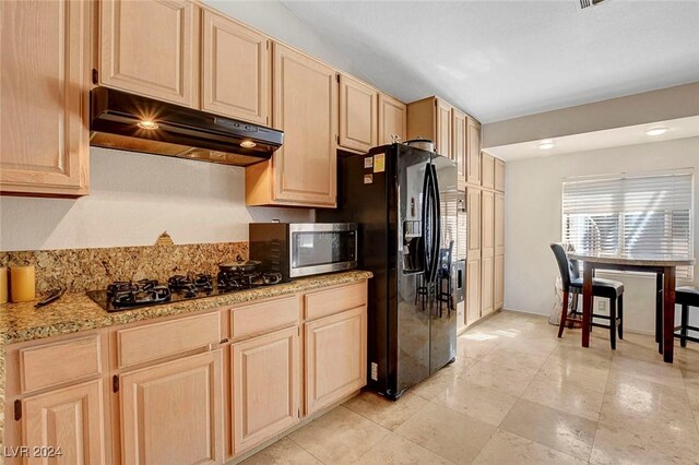 kitchen featuring light stone counters, light brown cabinets, and black appliances