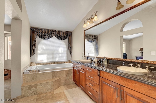 bathroom with tiled tub, vanity, and vaulted ceiling