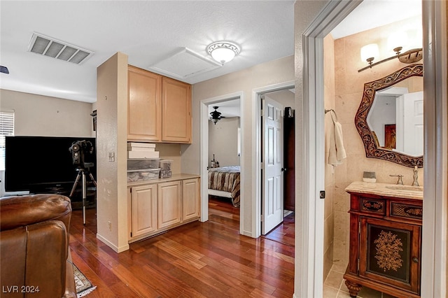 kitchen with a textured ceiling, light brown cabinetry, dark hardwood / wood-style floors, and sink