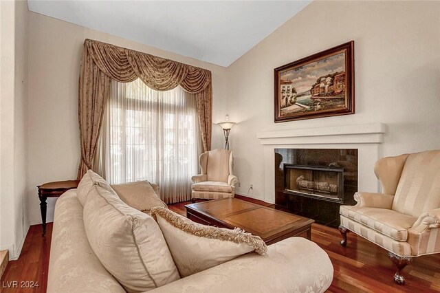 living area with hardwood / wood-style flooring, a tiled fireplace, and vaulted ceiling