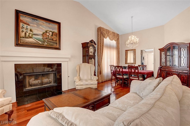 living room with a notable chandelier, lofted ceiling, dark hardwood / wood-style floors, and a fireplace