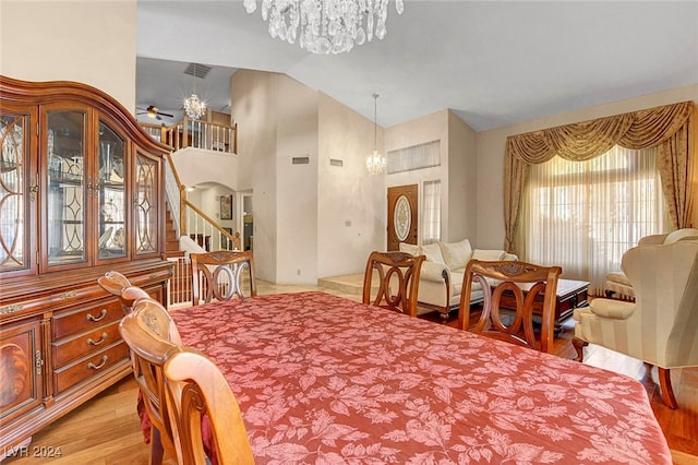 dining area with vaulted ceiling, an inviting chandelier, and light hardwood / wood-style flooring