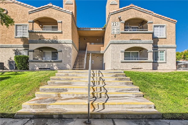 view of front of house featuring a balcony, central air condition unit, and a front yard