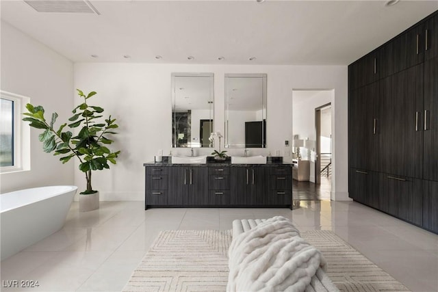 full bathroom with tile patterned flooring, a freestanding tub, visible vents, baseboards, and double vanity