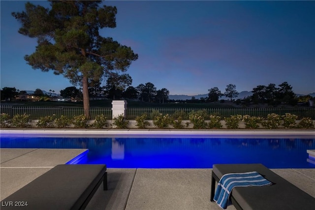 pool at dusk featuring a fenced in pool, a patio area, and a fenced backyard