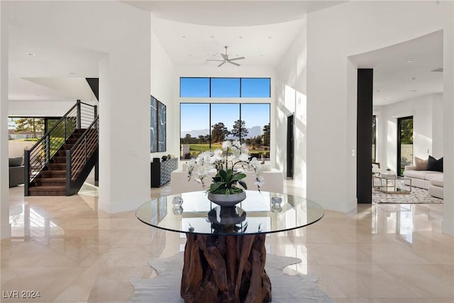 interior space with marble finish floor, a towering ceiling, baseboards, and stairs