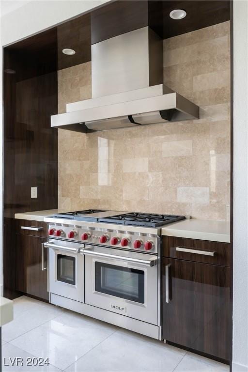 kitchen featuring range with two ovens, light countertops, wall chimney range hood, and modern cabinets