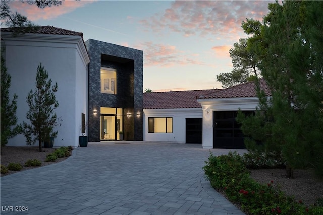 view of front of property featuring a tiled roof, decorative driveway, an attached garage, and stucco siding