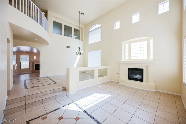 unfurnished living room with a high ceiling, plenty of natural light, and light tile patterned floors