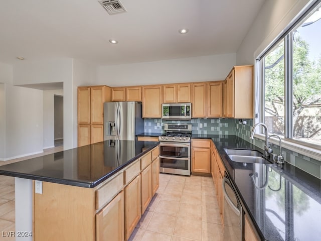 kitchen featuring a center island, backsplash, sink, light tile patterned floors, and stainless steel appliances