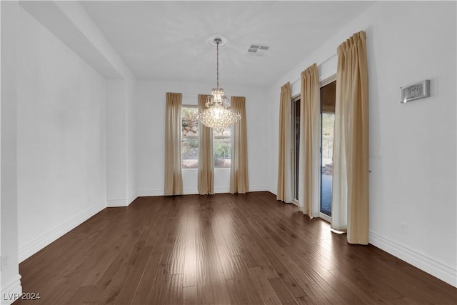 unfurnished dining area with dark wood finished floors, baseboards, visible vents, and an inviting chandelier