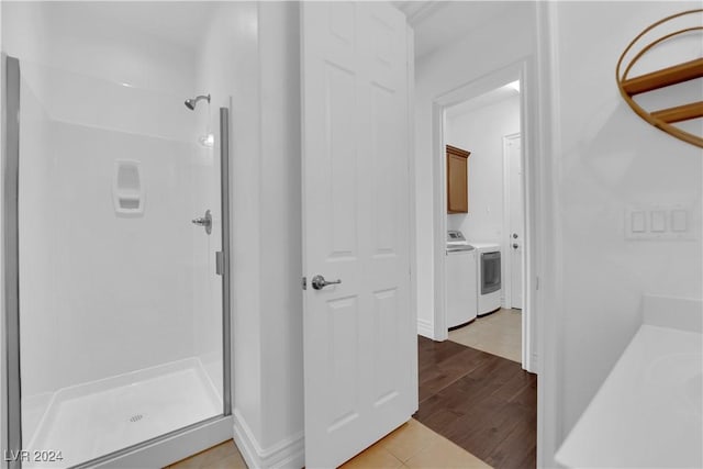 bathroom featuring washer and clothes dryer, a shower stall, and wood finished floors