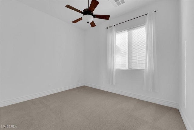 carpeted spare room with baseboards, visible vents, and ceiling fan