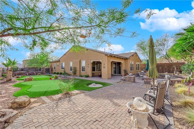 rear view of property with a patio area, stucco siding, an outdoor fire pit, and fence