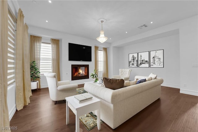 living area featuring dark wood finished floors, a glass covered fireplace, recessed lighting, and visible vents