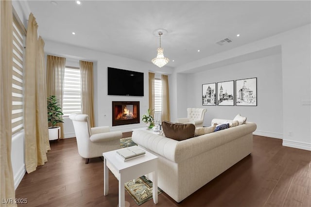 living area with dark wood finished floors, visible vents, recessed lighting, and a glass covered fireplace
